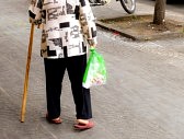 37890715-old-woman-walking-with-a-cane-down-the-street-of-the-city
